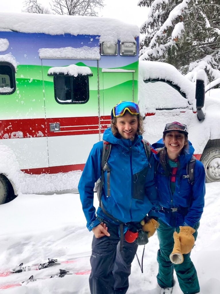 Malla Keefe and her partner Jordan standing outside in the snow in front of their converted ambulance-turned-tiny home