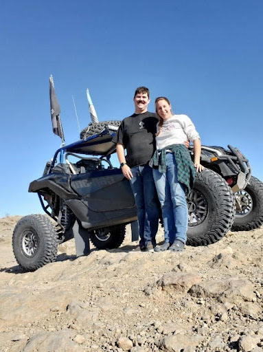 Mariellen Van Nieuwenhuyzen and her husband standing in front of their desert OHV.