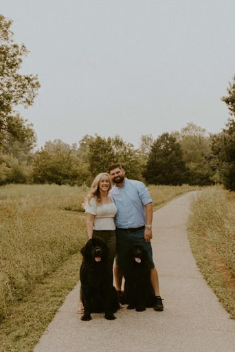 Samantha Carson and her husband Taylor standing behind their two newfoundland dogs outdoors in Boise, Idaho.