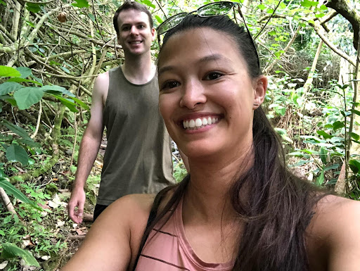 Sydney Holmes and her husband Rok Holmes taking a selfie in a jungle type of landscape.